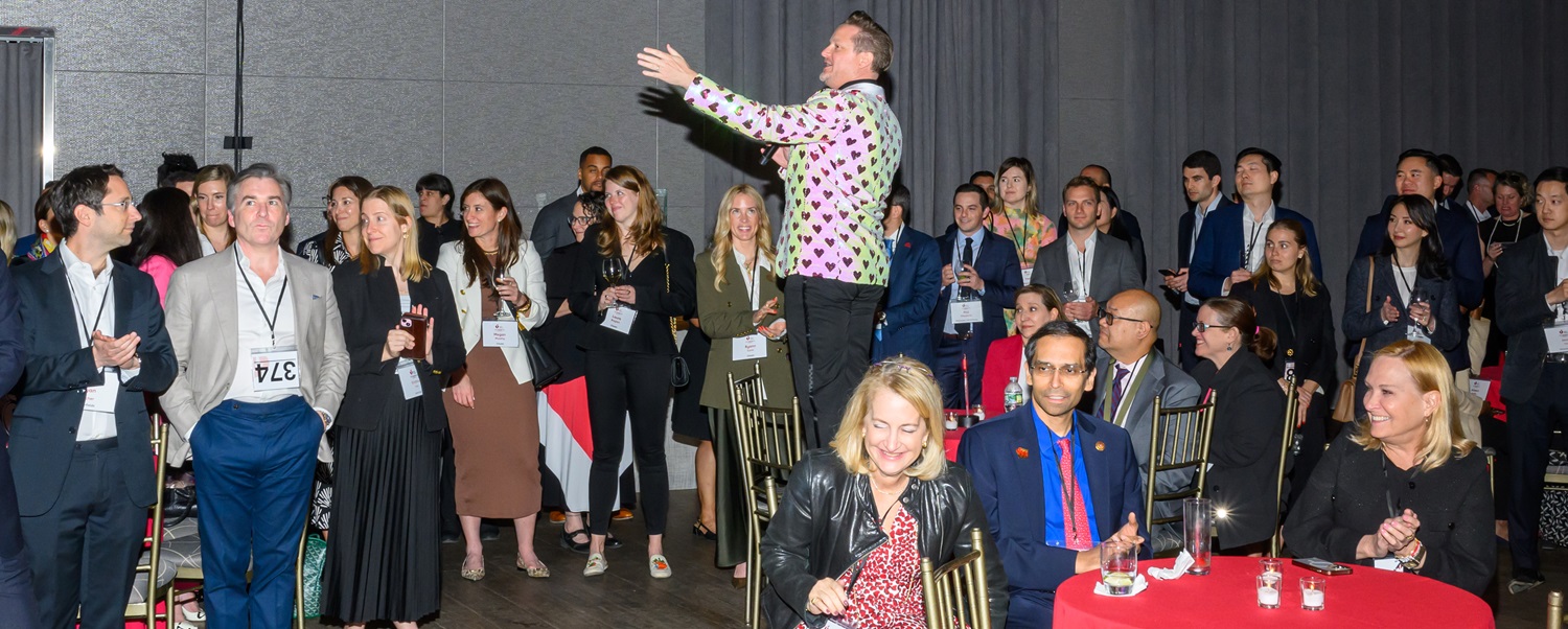 Man standing on a chair in the middle of a group of people.